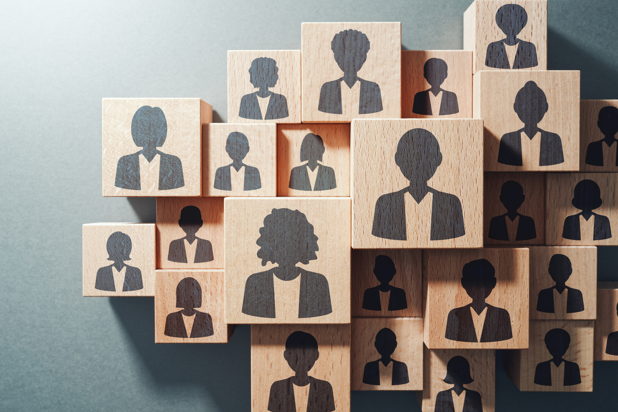 Holzklötze mit verschiedenen Silhouetten von Personen in Business-Kleidung.